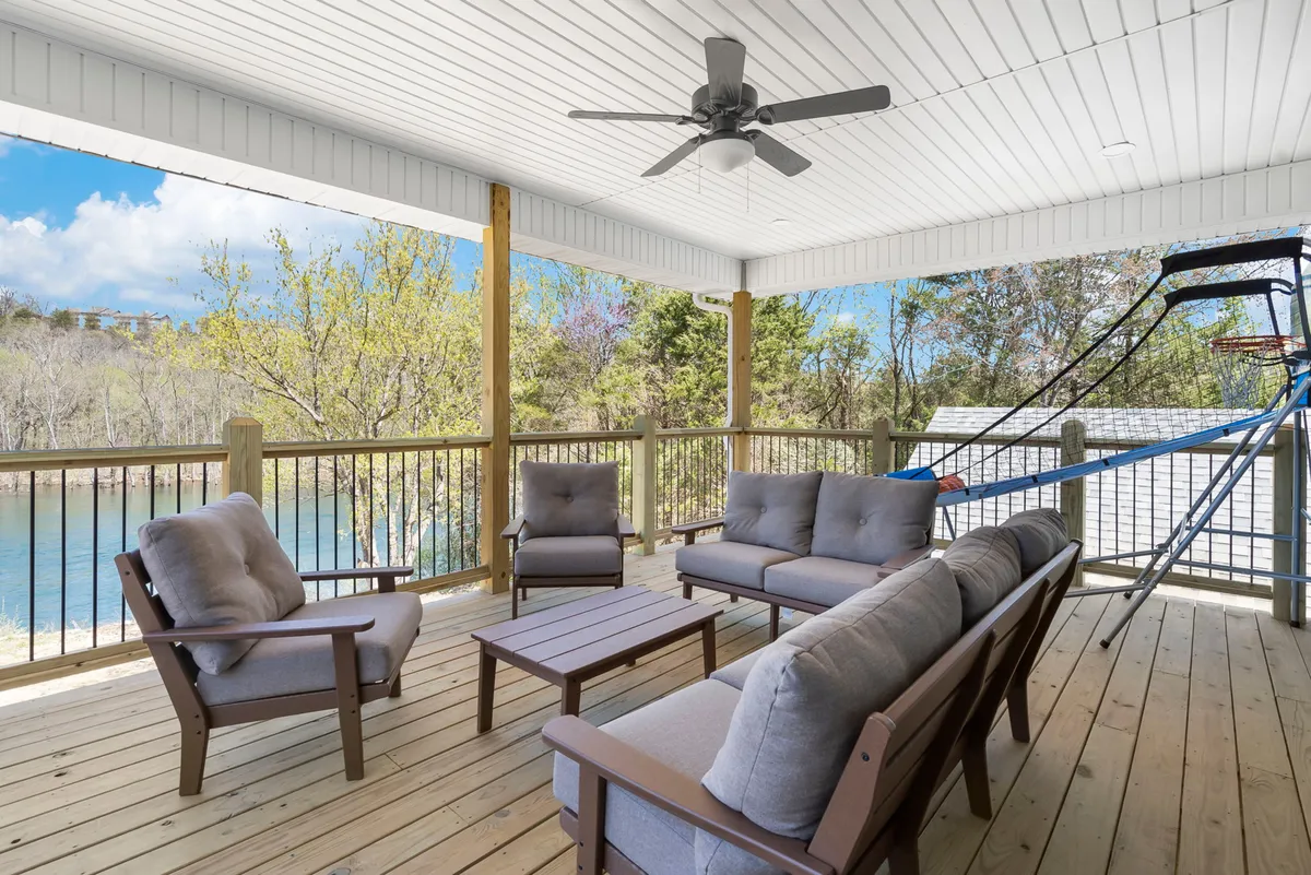 A welcoming outdoor seating area with comfortable chairs is set on decking overlooking the water. A basketball hoop and scenic views complement the inviting atmosphere, ideal for both relaxation and group activities.