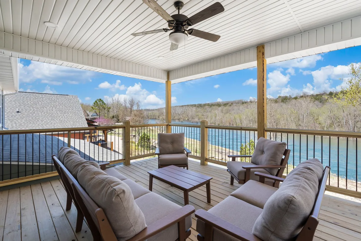 This exterior image features a seating arrangement overlooking a peaceful river, with a ceiling fan above and lush surroundings. The tranquil setting offers space for relaxing, socializing, and enjoying unobstructed views of the natural landscape.