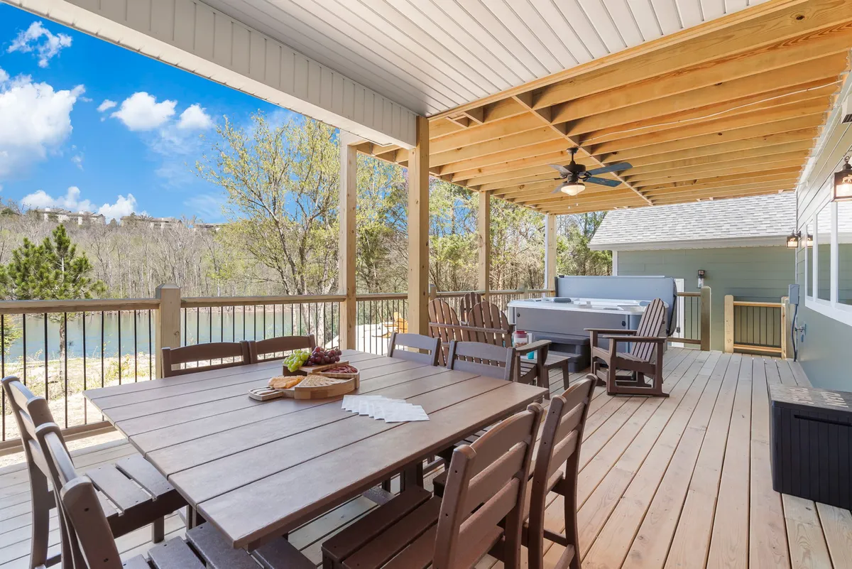 This exterior shot features a dining table and hot tub on a spacious deck with beautiful nature views. It suggests relaxation after a day outdoors, with space for al fresco dining and unwinding in the hot tub while surrounded by the wooded landscape.