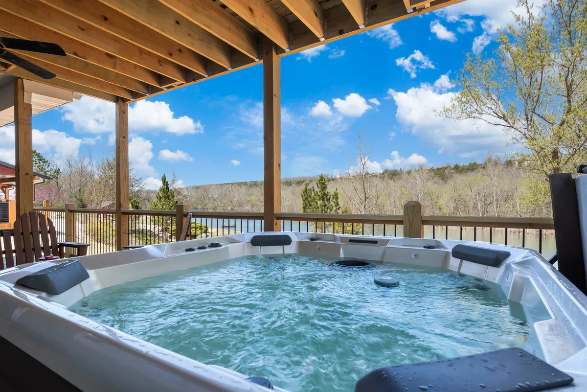 A relaxing exterior scene featuring a hot tub on a wooden deck, overlooking a scenic landscape bathed in sunset light. The setup is perfect for unwinding after a day on the water, with room for friends or family to gather and enjoy the view.